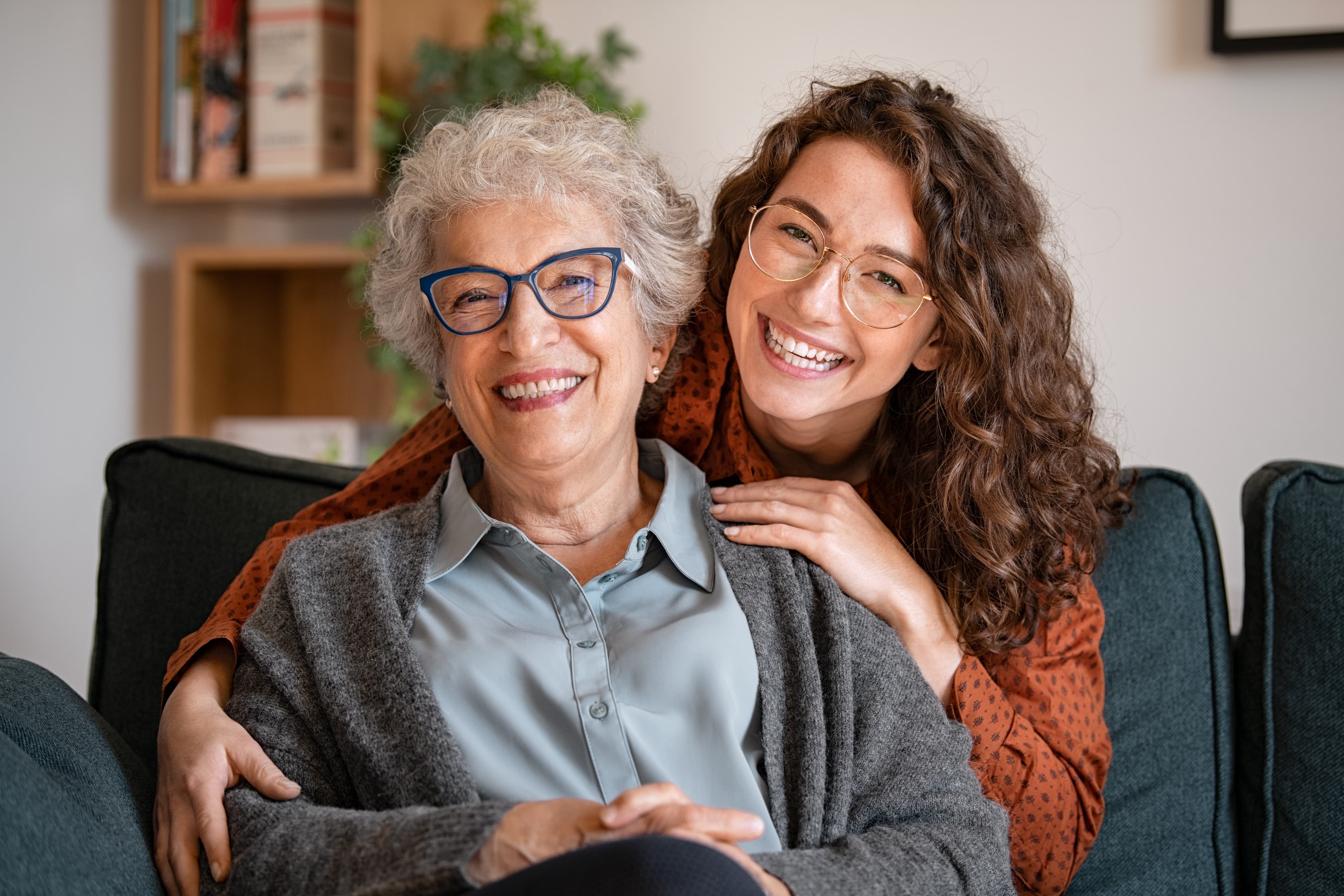 Smiling caregiver sitting with an older woman at home